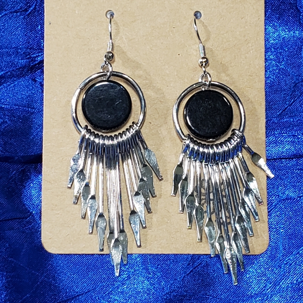 Black disc earrings with hanging daggers. Not sharp but pointy.